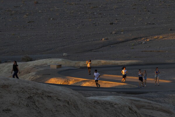 People run to get sunset photos at Zabriskie Point on Saturday, July 8, 2023, in Death Valley National Park, Calif. July is the hottest month at the park with an average high of 116 degrees (46.5 Celsius). (AP Photo/Ty ONeil)