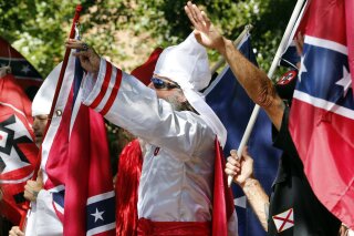 In this Saturday, July 8, 2017 photo, Klan members salute during a KKK rally in Justice Park, in Charlottesville, Va. The number of Ku Klux Klan chapters in the U.S. is plummeting as a new generation of khaki-clad racists rejects hoods and robes for a "hipper" brand of hate, according to a report Wednesday by an organization that tracks far-right extremists. (AP Photo/Steve Helber)