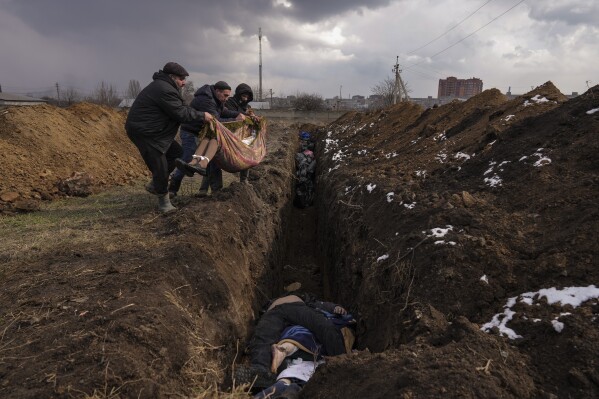Bodies are placed into a mass grave on the outskirts of Mariupol, Ukraine, Wednesday, March 9, 2022. (AP Photo/ Evgeniy Maloletka)