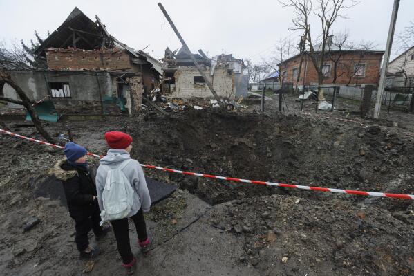 Children look at a crater created by an explosion in a residential area after Russian shelling in Solonka, Lviv region, Ukraine, Wednesday, Nov. 16, 2022. (AP Photo/Mykola Tys)
