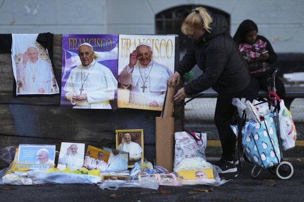 Una vendedora callejera acomoda pósters del papa Francisco fuera de la catedral de Buenos Aires, el sábado 26 de abril de 2025. (AP Foto/Natacha Pisarenko)