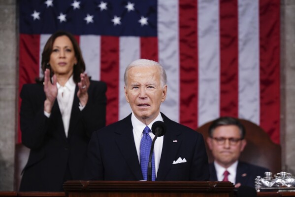 President Joe Biden delivers the State of the Union address to a joint session of Congress at the Capitol, Thursday, March 7, 2024, in Washington. Standing at left is Vice President Kamala Harris and seated at right is House Speaker Mike Johnson, R-La. (Shawn Thew/Pool via AP)