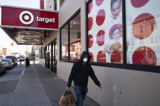 FILE - In this April 6, 2020 file photo, a customer wearing a mask carries his purchases as he leaves a Target store during the coronavirus pandemic, in the Brooklyn borough of New York. Target says it will spend a a total of more than $2 billion at Black-owned businesses by 2025 as part of its effort to advance racial equity. As part of its program, the Minneapolis-based discounter will add products from more than 500 Black-owned businesses across all types of merchandising areas. (AP Photo/Mark Lennihan, File)