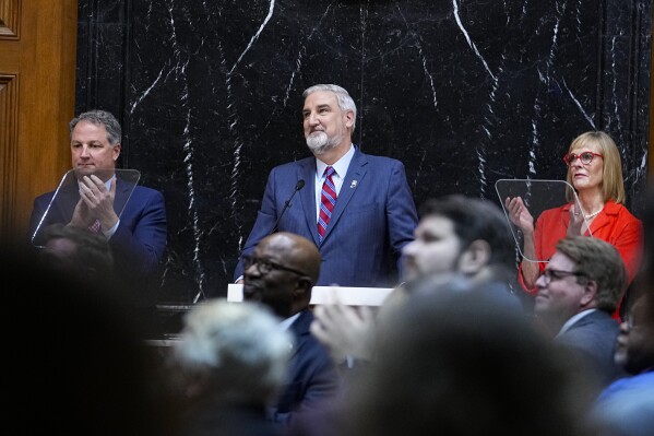 Indiana Gov. Eric Holcomb, center, and others look to the balcony during his State of the State address to a joint session of the General Assembly at the Statehouse, Tuesday, Jan. 9, 2024, in Indianapolis. (AP Photo/Darron Cummings)