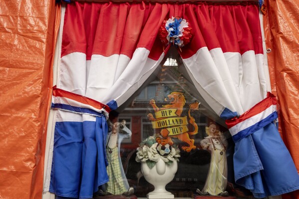 Orange tarp, orange bunting, and Dutch national flags decorate a window in Marktweg street in The Hague, Netherlands, Thursday June 13, 2024, one day ahead of the start of the Euro 2024 Soccer Championship. (AP Photo/Peter Dejong)