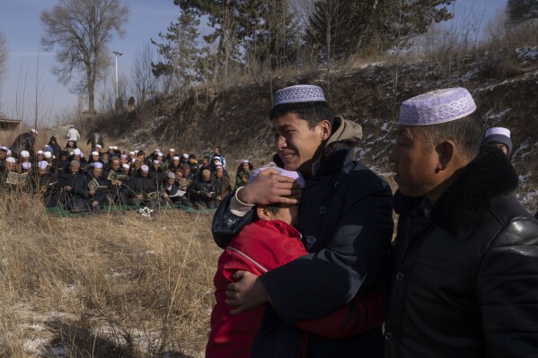 Ten years old Ma Yuanke, in red, griefs as his mother Han Suofeiya who was killed in an earthquake is buried at a cemetery in Yangwa village near Dahejia town in northwestern China's Gansu province, Wednesday, Dec. 20, 2023. (AP Photo/Ng Han Guan)