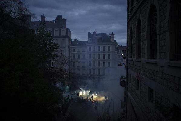 Demonstrators run in the tear gas during a demonstration in Lyon, central France, Friday, April 14, 2023. France's Constitutional Council on Friday approved an unpopular plan to raise the retirement age from 62 to 64, in a victory for President Emmanuel Macron after three months of mass protests over the legislation that have damaged his leadership. The decision dismayed or enraged critics of the pension plan, including protesters gathered outside Paris City Hall as the decision came down. (AP Photo/Laurent Cipriani)