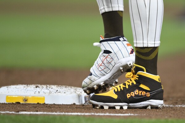 FILE - San Diego Padres' Fernando Tatis Jr. (23) wears cleats commemorating the Padres's 1980's and 1990's teams during a baseball game against the Chicago Cubs, Monday, April 8, 2024, in San Diego. Tatis plans to unveil 50 pairs of custom cleats this season in conjunction with his branding company, Xample, and Los Angeles-based Shoe Surgeon. The cleats will honor people, events and whatever strikes the 25-year-old Tatis' fancy. (AP Photo/Denis Poroy, File)