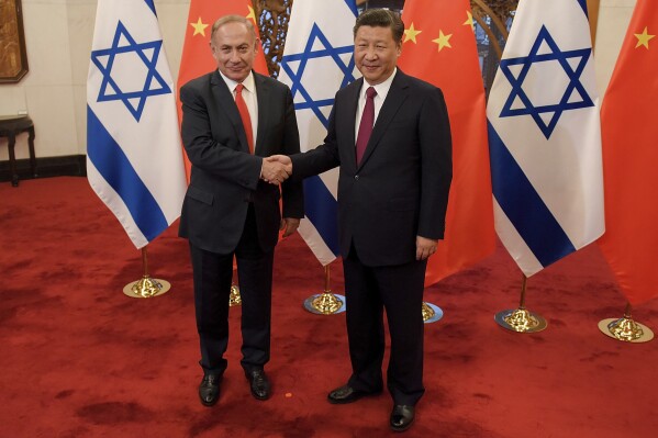 FILE - Israeli Prime Minister Benjamin Netanyahu, left, and Chinese President Xi Jinping pose for photographers ahead of their talks at Diaoyutai State Guesthouse on March 21, 2017 in Beijing, China. In June, Chinese President Xi Jinping hosted the Palestinian president in Beijing and invited the Israeli prime minister for an official state visit. Benjamin Netanyahu accepted, and China was on track for a bigger role in the region. Then came the attack, which has made Netanyahu’s trip uncertain and all the more so because of China's stated neutrality on the war. (Etienne Oliveau/Pool Photo via AP, File)