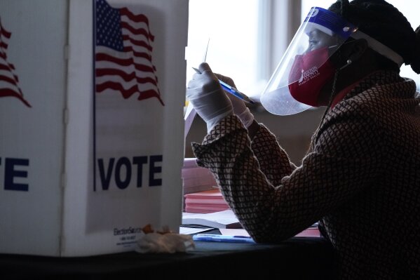 FILE - In this Nov. 3, 2020, file photo, a poll worker talks to a voter before they vote on a paper ballot on Election Day in Atlanta. Republican efforts to restrict voting access are taking shape in statehouses across the country with a flurry of legislation aimed at limiting measures that led to record turnout in the 2020 presidential election. (AP Photo/Brynn Anderson, File)