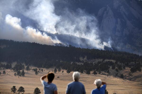 From left to right, Laura Tyson, Tod Smith and Rebecca Caldwell, residents of Eldorado Springs, watch as the NCAR fire burns in the foothills south of the National Center for Atmospheric Research, Saturday, March 26, 2022, in Boulder, Colo. The NCAR fire prompted evacuations in south Boulder and pre-evacuation warning for Eldorado Springs. (Helen H. Richardson/The Denver Post via AP)