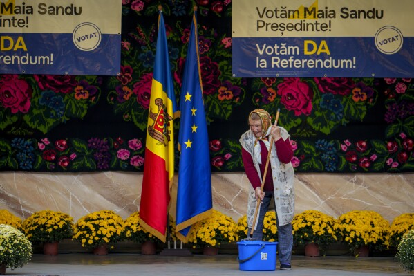 A woman mops a stage before an electoral rally of Moldova's President Maia Sandu in Magdacesti, Moldova, Thursday, Oct. 17, 2024, who is seeking a second term in office ahead of a presidential election and a referendum of whether to enshrine in Moldova's Constitution its path to European Union membership taking place on Oct.20. (AP Photo/Vadim Ghirda)