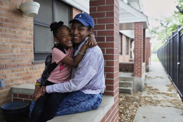 Millicent Brown, right, and her daughter, Nova Brown, 5, pose for a photo outside their home at a public housing complex before school on Wednesday, April 2, 2025, in Houston. (AP Photo/Ashley Landis)