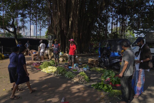 Vendors wait for customers at a vegetable market in Colombo, Sri Lanka, Wednesday, Dec. 13, 2023. The International Monetary Fund executive board has approved the release of $ 337 million second tranche of a bailout package to help Sri Lanka recover from its worst economic crisis. (AP Photo/Eranga Jayawardena)