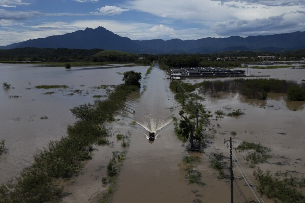 Residents cross a submerged road in a boat after deadly rainfall in Duque de Caxias, Brazil, Monday, Jan. 15, 2024. (AP Photo/Bruna Prado)