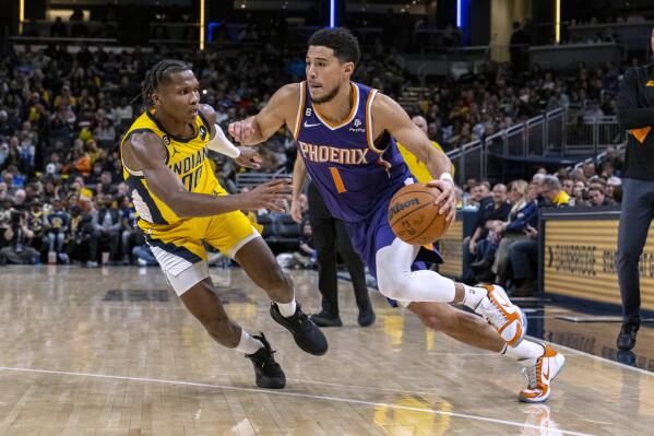 Phoenix Suns guard Devin Booker (1) drives against Indiana Pacers guard Bennedict Mathurin (00) during the second half of an NBA basketball game in Indianapolis, Friday, Feb. 10, 2023. (AP Photo/Doug McSchooler)