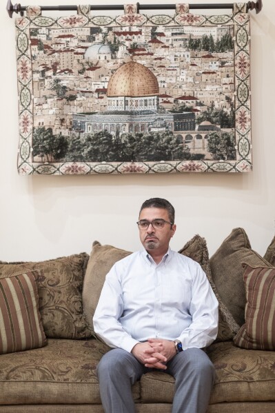 Dr. Emad Shehada, a Palestinian doctor sits under a picture of Jerusalem at his home in West Bloomfield, Mich. on Thursday, Oct. 26, 2023. The Detroit-area doctor is grieving the loss of at least 20 relatives killed during Israel's war against Hamas. (Junfu Han/Detroit Free Press via AP)