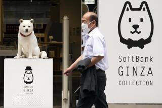 FILE - A man walks past a SoftBank shop in Tokyo on July 29, 2021. Japanese technology investor SoftBank Group reported Thursday, May 11, 2023, a loss of 970 billion yen ($7 billion) for the fiscal year that just ended — the second year in a row of red ink. (AP Photo/Eugene Hoshiko, File)