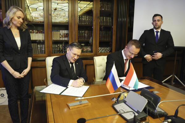 In this handout photo released by Communications Department of Rosatom, Alexey Likhachev, Director General of State Atomiс Energy Corporation Rosatom, left, and Peter Szijjarto, Minister of Foreign Affairs and Trade of Hungary sign a document during their meeting in Moscow, Russia, Tuesday, April 11, 2023. (Ivan Fedorenko, Communications Department of ROSATOM via AP)