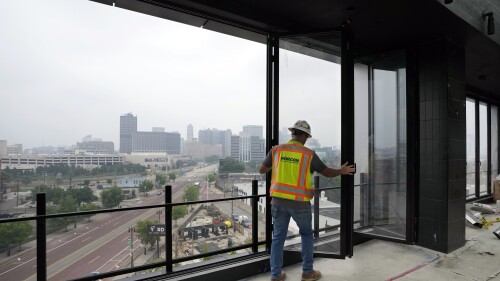 A worker opens the windows on the top floor of the new Godfrey Hotel, on June 27, 2023, in Detroit.  On July 18, 2013, a state-appointed trustee declared Detroit the largest city in the US to file for bankruptcy.  A decade later, the city has risen from the ashes of insolvency.  (AP Photo/Carlos Osorio)