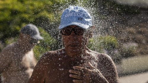 A bather takes a shower during a hot day at Alimos beach near Athens, Friday, July 14, 2023. Temperatures were starting to creep up in Greece, where a heatwave was forecast to reach up to 44 degrees Celsius in some parts of the country over the weekend. (AP Photo/Petros Giannakouris)