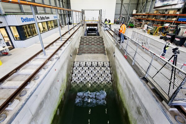 This photo taken in Jan. 2019 and made available by Deltares shows the flume wave tank in Delft, Netherlands, that is used to test structure designs for the strengthening work for the Afsluitdijk. With climate change bringing bigger storms and rising sea levels, one of the low-lying Netherlands’ key defenses against the sea is getting a major makeover. The 5-year project will see workers lay thousands of concrete blocks and raise parts of the 87-year-old Afsluititdijk dike. (Guus Schoonewille/Deltares via AP)