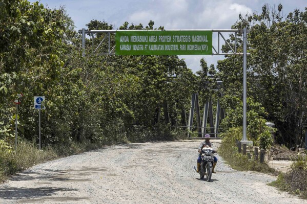 A motorist ride past the entrance to the construction site of the Kalimantan Industrial Park Indonesia (KIPI) in Mangkupadi, North Kalimantan, Indonesia on Thursday, Aug. 24, 2023. Writings on the sign at the gate read: "You are entering the area of national strategic project Kalimantan Industrial Park Indonesia." (AP Photo/Yusuf Wahil)