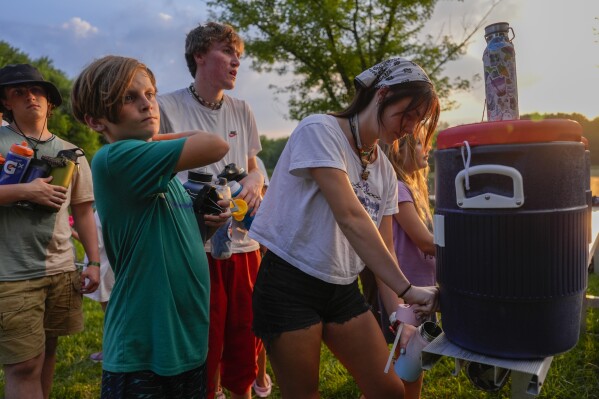 Counselor Izzy Kellar, of Dayton, Ohio, fills up her campers' water bottles, Thursday, June 20, 2024, at YMCA Camp Kern in Oregonia, Ohio. Experts say children can be more vulnerable to extreme heat than adults, and it's important to monitor the children and train counselors to respond to problems. (AP Photo/Joshua A. Bickel)