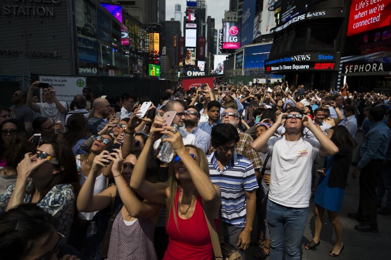 FILE - A crowd reacts to the view of a partial solar eclipse as it peaks at over 70% percent coverage on Monday, Aug. 21, 2017, in New York. (AP Photo/Michael Noble Jr.)