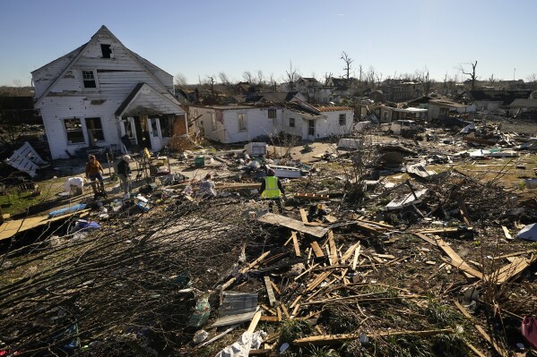 FILE - Volunteers help Martha Thomas, second from left, salvage property from her destroyed home, following tornadoes that tore through the area, in Mayfield, Kentucky, Dec. 13, 2021. (AP Photo/Gerald Herbert, File)