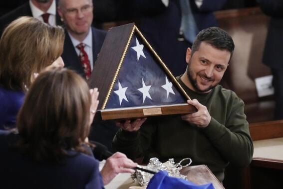 Ukrainian President Volodymyr Zelenskyy holds an American flag that was gifted to him by House Speaker Nancy Pelosi of Calif., after he addressed a joint meeting of Congress on Capitol Hill in Washington, Wednesday, Dec. 21, 2022. House Speaker Nancy Pelosi of Calif., left, and Vice President Kamala Harris, to her right. (AP Photo/J. Scott Applewhite)