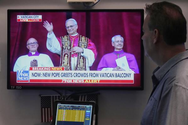 Trader Bob Hannan watches a television screen on the trading floor of the New York Stock Exchange as newly elected Pope Leo XIV appears at the balcony of St. Peter's Basilica at the Vatican, Thursday, May 8, 2025. (AP Photo/Richard Drew)