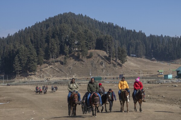 A family takes a horse ride in Gulmarg, northwest of Srinagar, Indian controlled Kashmir, Saturday, Jan. 13, 2024. There is hardly any snow at Asia's largest ski terrain in Gulmarg where thousands of domestic and international tourists would usually visit to ski and sledge its stunning snowscape in winter.(AP Photo/Dar Yasin)