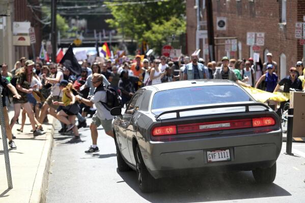 FILE - In this Aug. 12, 2017, file photo, a vehicle drives into a group of protesters demonstrating against a white nationalist rally in Charlottesville, Va. A trial is beginning in Charlottesville, Virginia to determine whether white nationalists who planned the so-called “Unite the Right” rally will be held civilly responsible for the violence that erupted. (Ryan M. Kelly/The Daily Progress via AP, File)