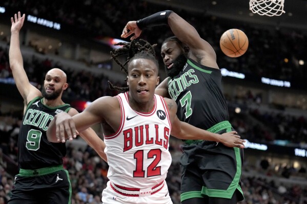 Chicago Bulls' Ayo Dosunmu (12) braces for a fall after Boston Celtics' Jaylen Brown (7) blocked his shot as Celtics' Derrick White defends during the second half of an NBA basketball game Thursday, Feb. 22, 2024, in Chicago. (AP Photo/Charles Rex Arbogast)
