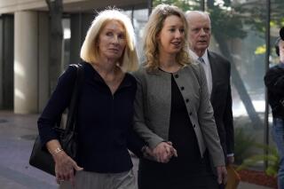 FILE - Former Theranos CEO Elizabeth Holmes, center, her mother, Noel Holmes, left, and father, Christian Holmes IV, arrive at federal court in San Jose, Calif., Thursday, Sept. 1, 2022. Elizabeth Holmes on Tuesday, Sept. 6, 2022, requested a new trial in documents asserting that a key witness who testified against her now regrets the role he played in her criminal conviction for lying to investors about the flaws in a blood-testing technology that she had hailed as a medical breakthrough. (AP Photo/Jeff Chiu, File)