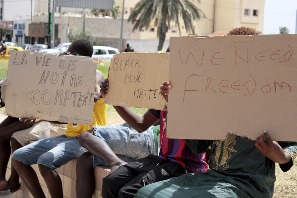 FILE - Migrants hold placards reading "Black Lives Matter", left, in French, during a gathering in Sfax, Tunisia's eastern coast, on July 7, 2023. Migration activists are sounding the alarm this week about mass expulsions and arbitrary arrests in Tunisia, where authorities are seeing more migrants arrive for attempted Mediterranean crossings from the North African nation to Europe. The Tunisian Forum for Economic and Social Rights on Monday, Jan. 9, 2024 accused the government of waging a campaign of repression against migrants at the expense of humanitarian concerns, “to satisfy European blackmail and ensure a steady stream of financial and logistical support.” (AP Photo, File)