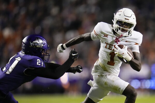 Texas wide receiver Xavier Worthy (1) avoids a tackle by TCU safety Bud Clark (21) during the first half of an NCAA college football game, Saturday, Nov. 11, 2023, in Fort Worth, Texas. (AP Photo/Julio Cortez)