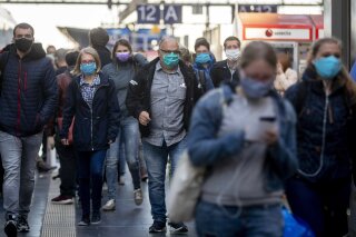 FILE - In this April 27, 2020, file photo, passengers wearing face masks arrive in the main train station in Frankfurt, Germany. Germany launched a coronavirus tracing app Tuesday, June 16, 2020, that officials say is so secure even government ministers can use it. Smartphone apps have been touted as a high-tech tool in the effort to track down potential COVID-19 infections. But governments in privacy-conscious Europe have run into legal and cultural hurdles trying to reconcile the need for effective tracing with the continent’s strict data privacy standards. (AP Photo/Michael Probst, File)