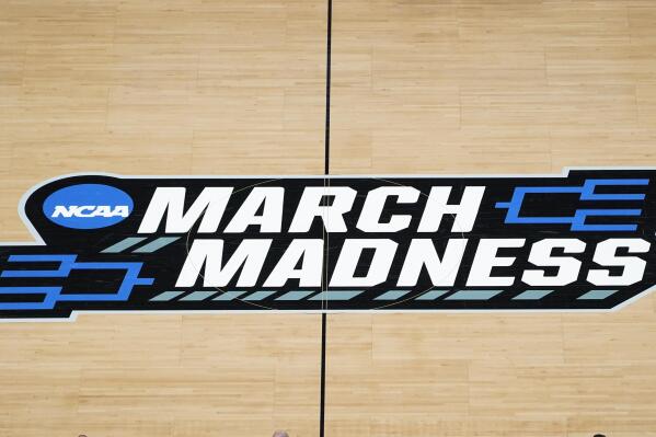 FILE -The March Madness logo is shown on the court during the first half of a men's college basketball game in the first round of the NCAA tournament at Bankers Life Fieldhouse in Indianapolis, Saturday, March 20, 2021. Kansas, Villanova, North Carolina and Duke will play in the first Final Four to take place under the new world of “name, image and likeness” endorsements in college sports. It allows college players to earn money through endorsements. (AP Photo/Paul Sancya, File)