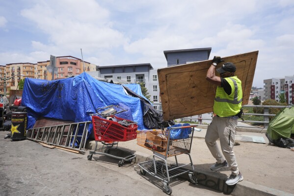 Jay Joshua cleans up around a homeless encampment where he currently lives, Monday, May 12, 2025, in Los Angeles. (AP Photo/Damian Dovarganes)