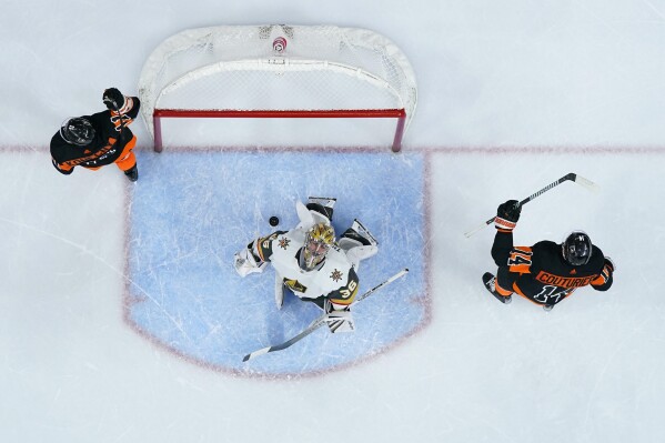 Vegas Golden Knights' Logan Thompson, center, reacts after giving up the game-winning goal to Philadelphia Flyers' Sean Couturier, right, as Travis Konecny, left, skates past during overtime in an NHL hockey game, Saturday, Nov. 18, 2023, in Philadelphia. (AP Photo/Matt Slocum)