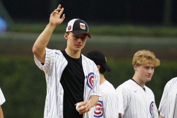 Chicago Blackhawks' No. 1 overall pick in the NHL draft Connor Bedard, left, waves before throwing out a ceremonial first pitch before a baseball game between the Chicago Cubs and the Cleveland Guardians, Sunday, July 2, 2023, in Chicago. (AP Photo/David Banks)