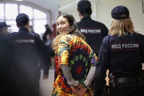 FILE - Sasha Skochilenko, a 33-year-old artist and musician, walks escorted by officers to the court room for a hearing in the Vasileostrovsky district court in St. Petersburg, Russia, on Oct. 19, 2023. Skochilenko was arrested in April 2022 on the charges of spreading false information about the army after replacing supermarket price tags with ones decrying what the Kremlin insists on calling a 