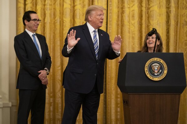 Treasury Secretary Steven Mnuchin watches as President Donald Trump jokes about touching the microphone with Jackie Krick, CEO and founder of ECU Communications, during an event about the Paycheck Protection Program used to support small businesses during the coronavirus outbreak, in the East Room of the White House, Tuesday, April 28, 2020, in Washington. (AP Photo/Evan Vucci)
