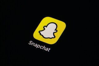 FILE - The icon for Snapchat is seen on a smartphone, Feb. 28, 2023, in Marple Township, Pa. Investigators in Massachusetts are pursuing criminal charges against six teens who they say participated in “a hateful, racist online chat that included heinous language, threats, and a mock slave auction” using Snapchat. (AP Photo/Matt Slocum, File)