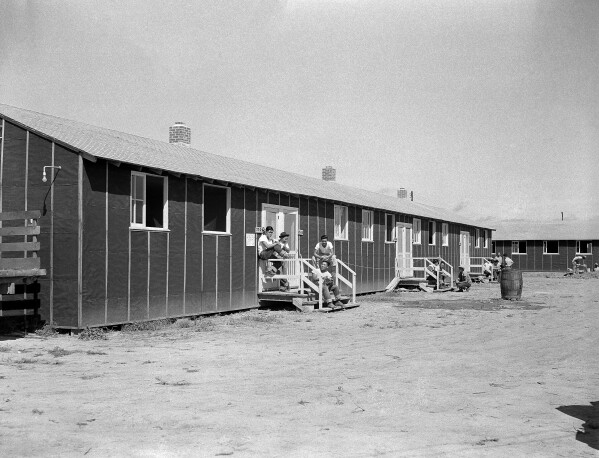 FILE - Relocated Japanese Americans sit on small front porches at barracks at Rohwer Relocation Center near Rohwer, Ark., on Sept. 21, 1942. On Feb. 19, 1942, following the attack by Imperial Japan on Pearl Harbor and the United States' entry to WWII, President Franklin D. Roosevelt signed Executive Order 9066 authorizing the incarceration of people of Japanese ancestry. (AP Photo/Horace Cort, File)
