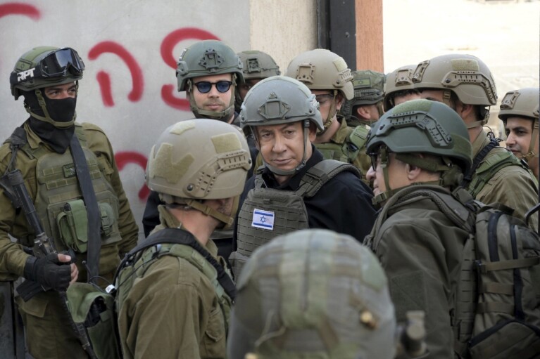Israeli Prime Minister Benjamin Netanyahu, center, wears a protective vest and helmet as he receives a security briefing with commanders and soldiers in the northern Gaza Strip, Monday, Dec. 25, 2023. (Avi Ohayon/GPO/Handout via AP)