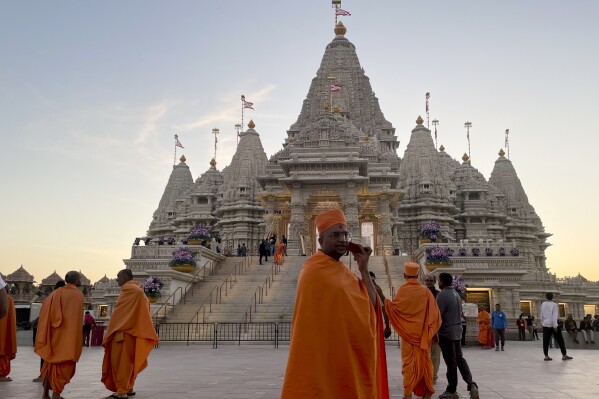 Monks in saffron robes walk in front of the BAPS Swaminarayan Akshardham, the largest Hindu temple outside India in the modern era, on Wednesday Oct. 4, 2023, in Robbinsville, N.J. The temple was partly built using marble from Italy and limestone from Bulgaria hand-carved by artisans in India and shipped to New Jersey. (AP Photo/Luis Andres Henao)