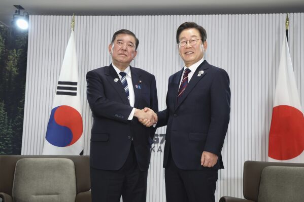 Japanese Prime Minister Shigeru Ishiba, left, and South Korean President Lee Jae Myung, right, shake hands ahead of a bilateral meeting on the sidelines of the G7, in Kananaskis, Alberta, on June 17, 2025. (Kyodo News via AP)